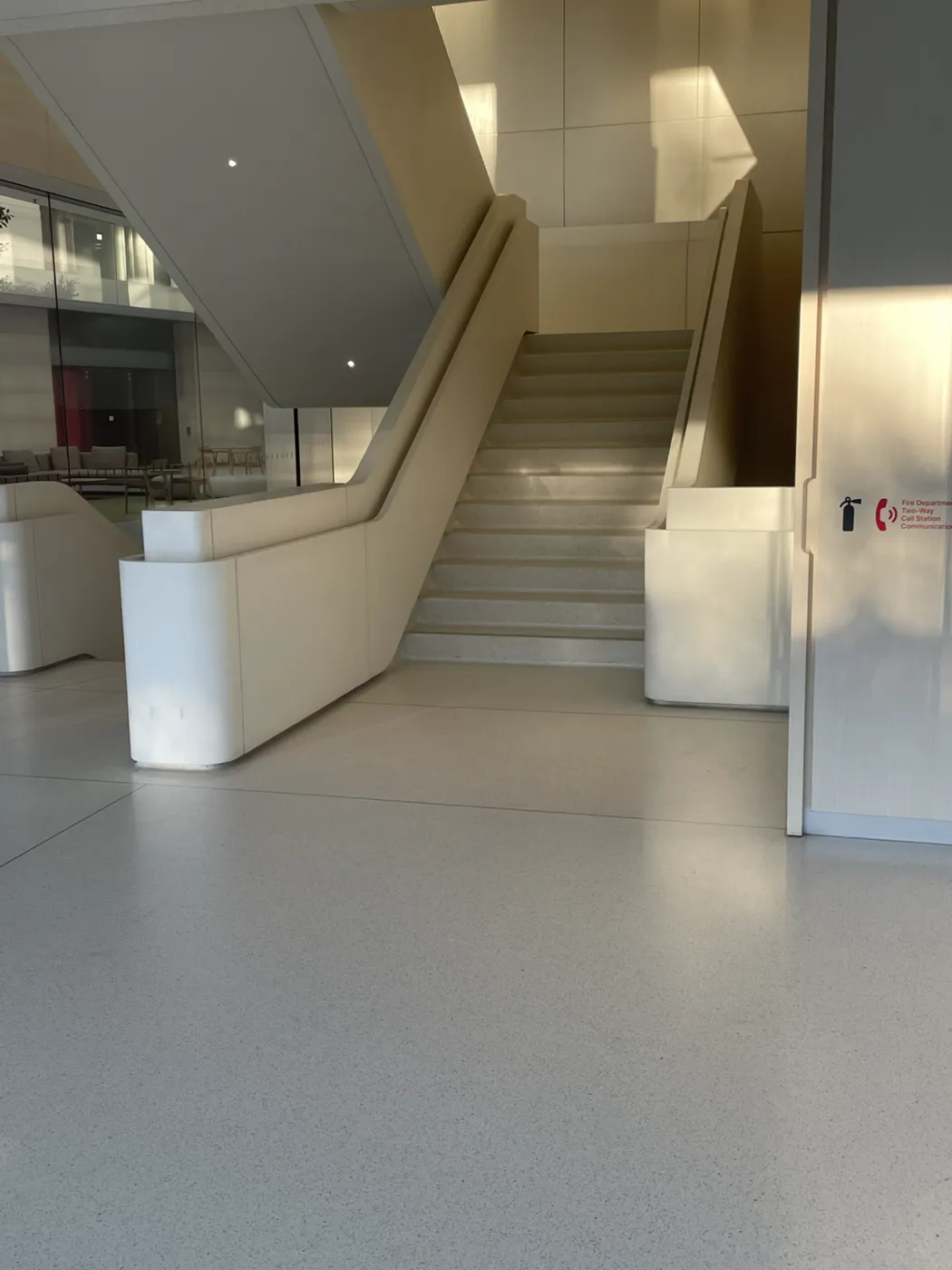 An interior stair with solid sculpted balustrades and rounded ends in a pale monolithic finish