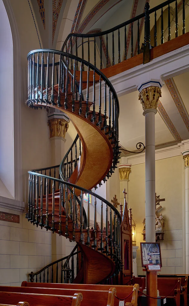 The Loretto Chapel staircase — a free-standing wooden double helix rising two full turns to the choir loft, no central support