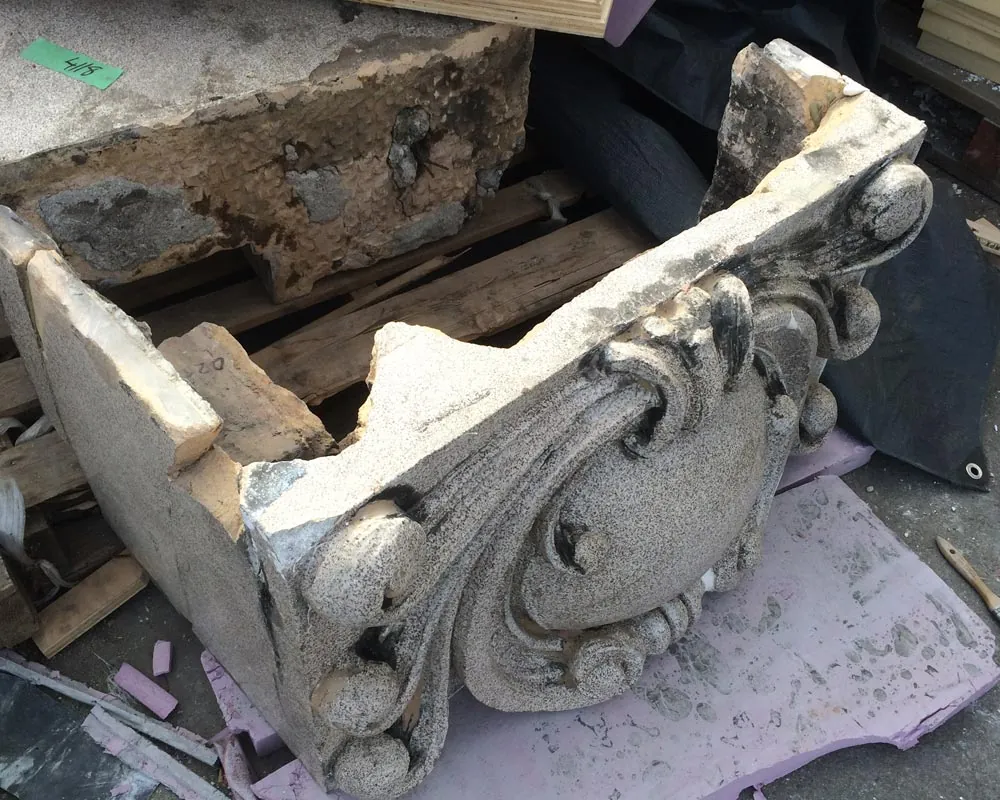 A damaged original terracotta ornament, chalk-numbered for cataloguing, on a pallet