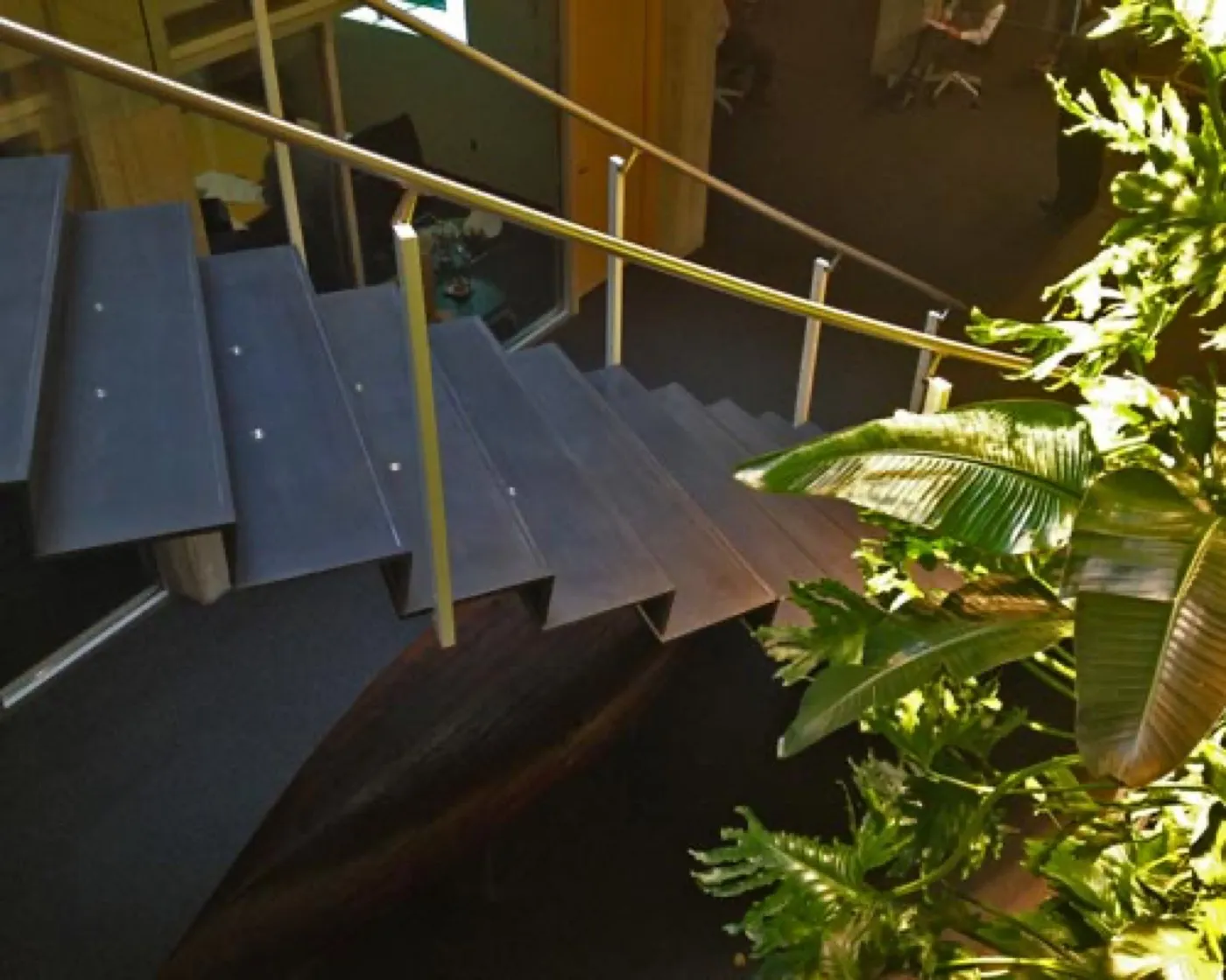 The finished Perkins&Will stair — dark UHPC treads rising past a glass balustrade and a living wall