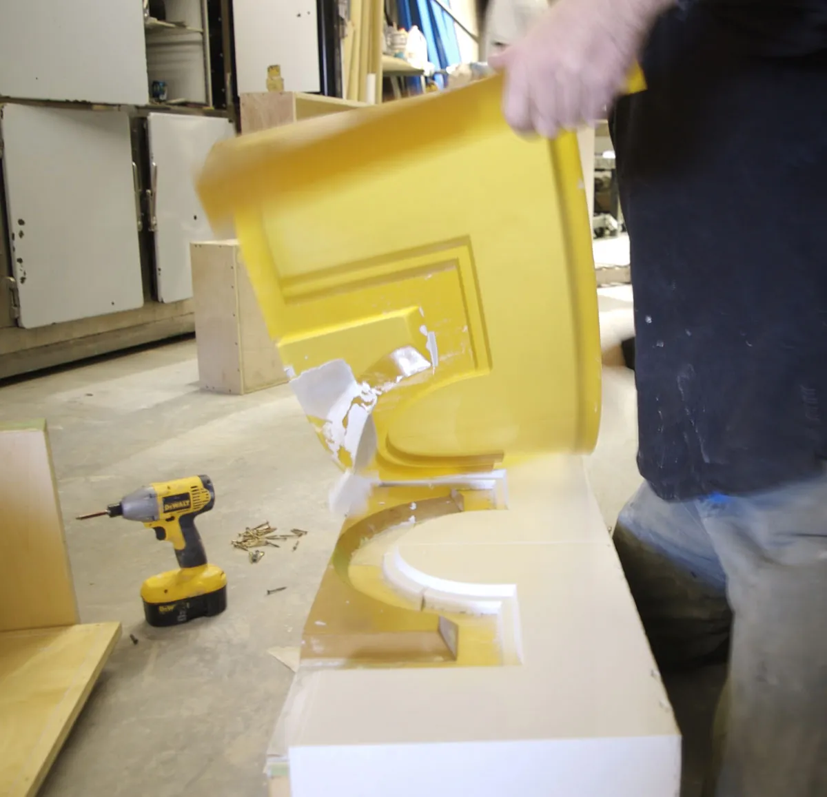 A shop worker peels a yellow rubber mold off a freshly cast white Ductal column profile