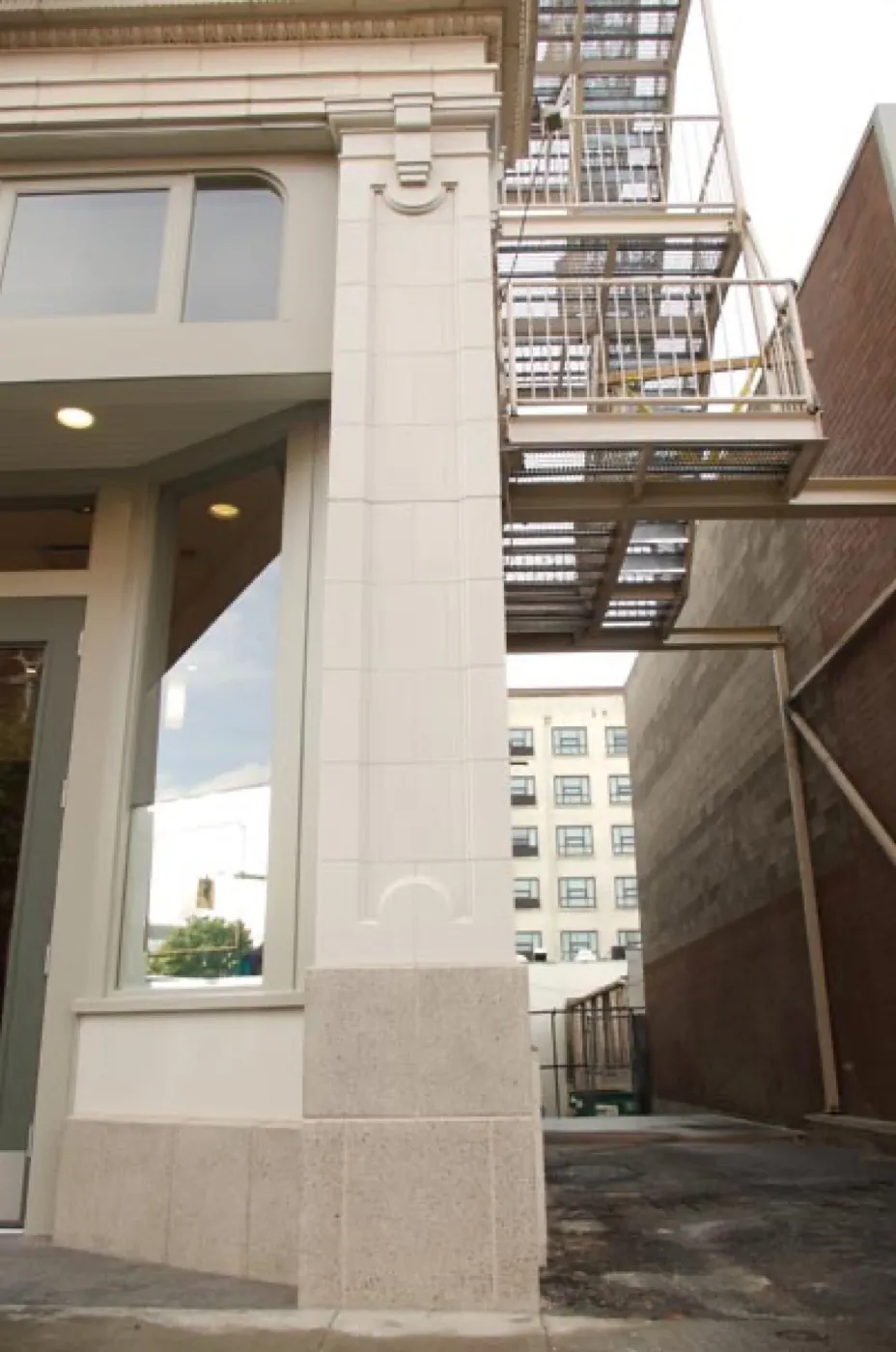 A finished white column at street level, the cast tile texture and grout lines running its full height