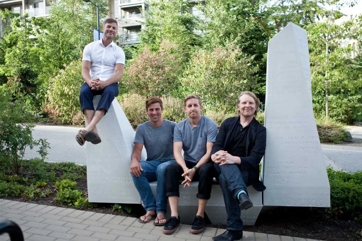 Four people sitting on the white EcoSoMo modules in a landscaped courtyard at SFU