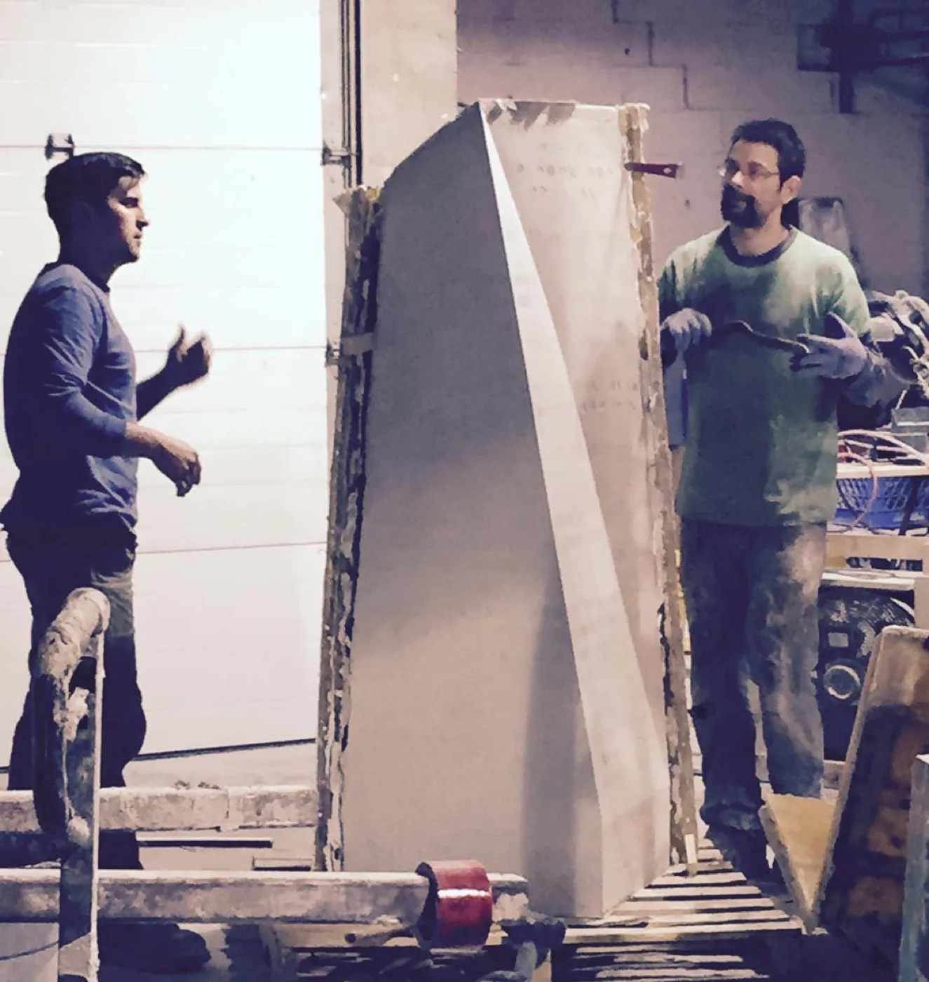 Two of the shop crew either side of a full-height EcoSoMo module still in its mold frame