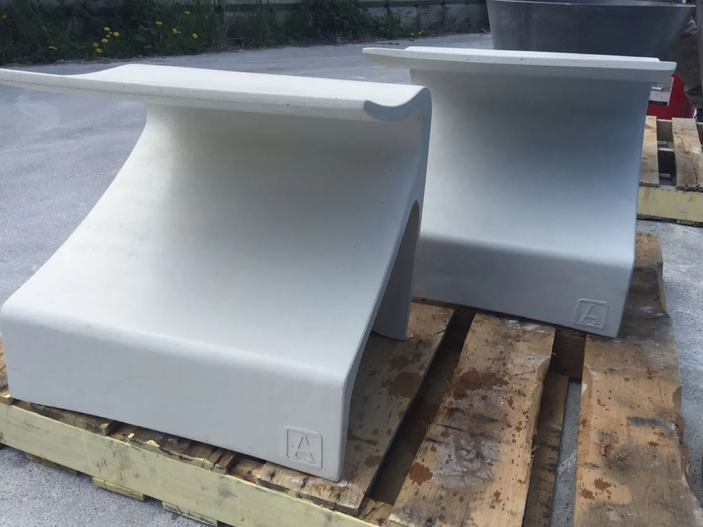 Two finished white Sofi benches on pallets in the yard, each a single sweeping surface