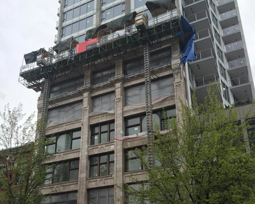 The Columbia Street facade under restoration, swing stages overhead and replacement blocks set into the upper storeys