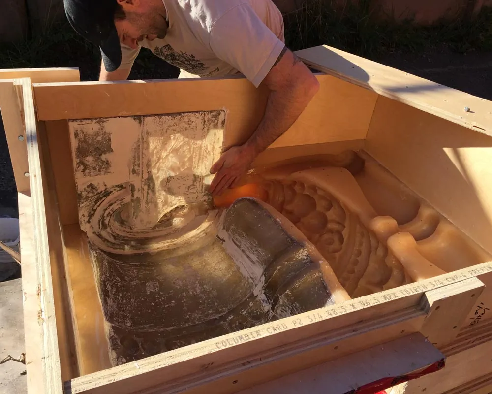 A mold-maker fits a rubber liner into a wood mold crate for a Trapp Block terracotta profile