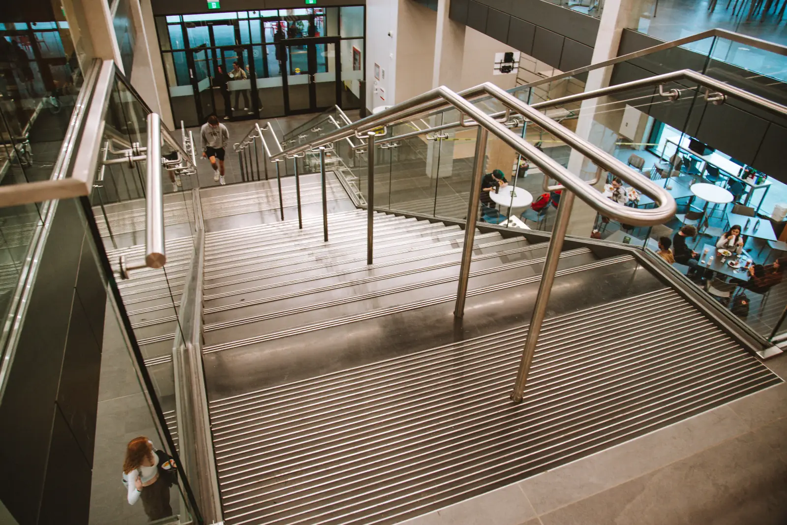 The UVic switchback feature stair from above, descending into the dining hall as students cross below