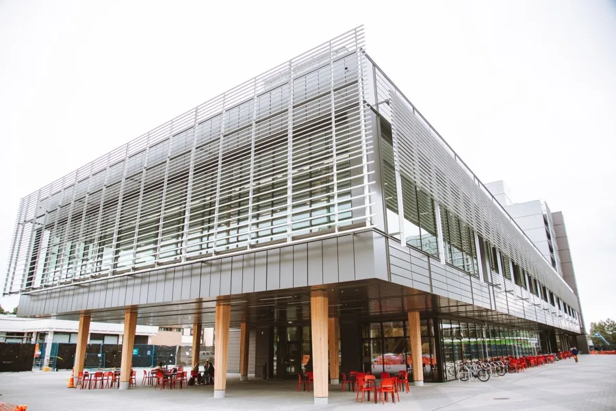 The student housing and dining building from outside, its glazed and screened facade along the campus edge